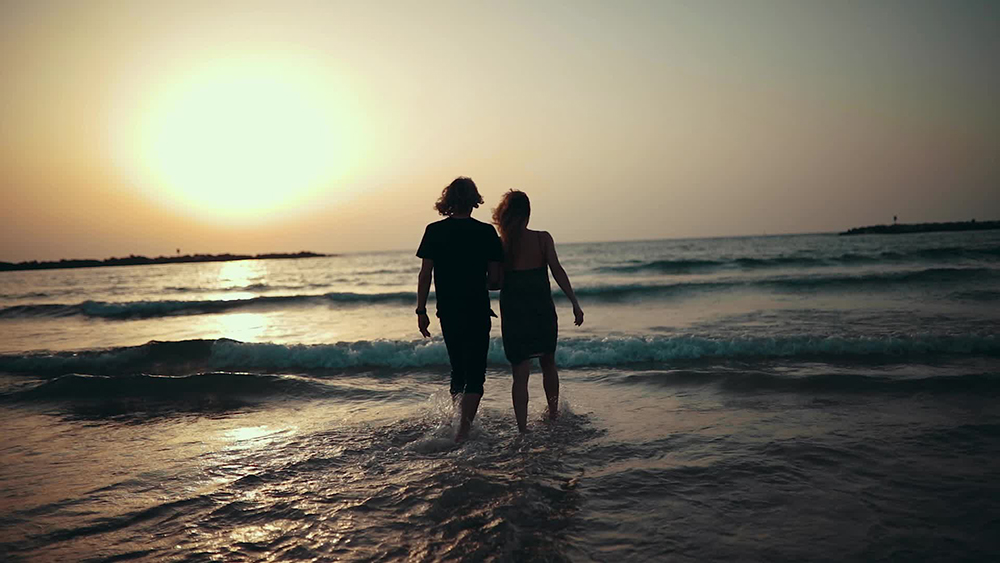 Couple walking on beach at sunset